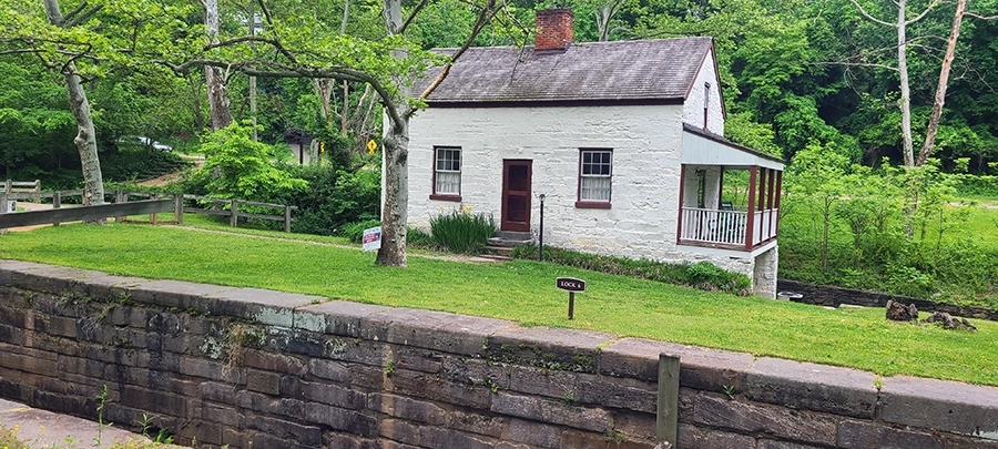 A small stone building with whitewash on the side of a canal.