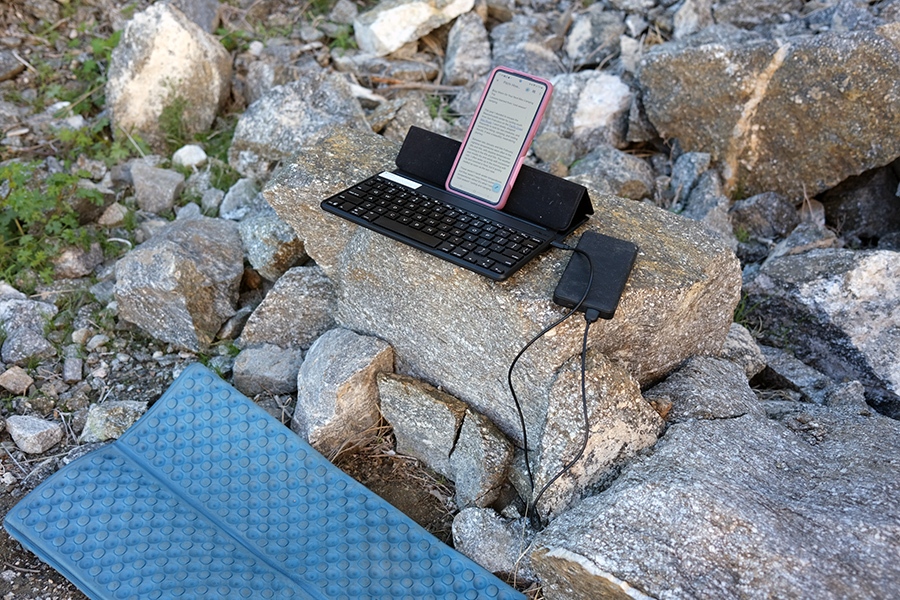Laura's phone, keyboard, and power supply set up in front of her sitting pad.