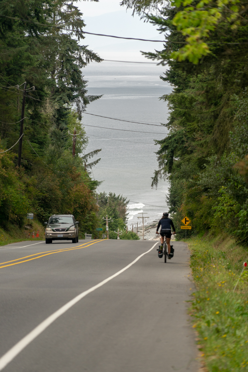 A cyclist on a road from behind going downhill.