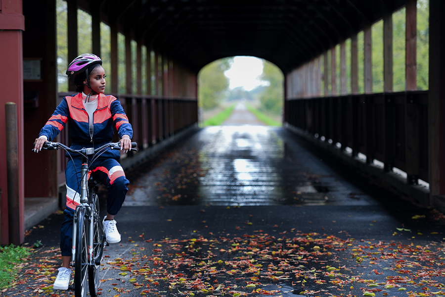 A woman bikes across a wet covered bridge