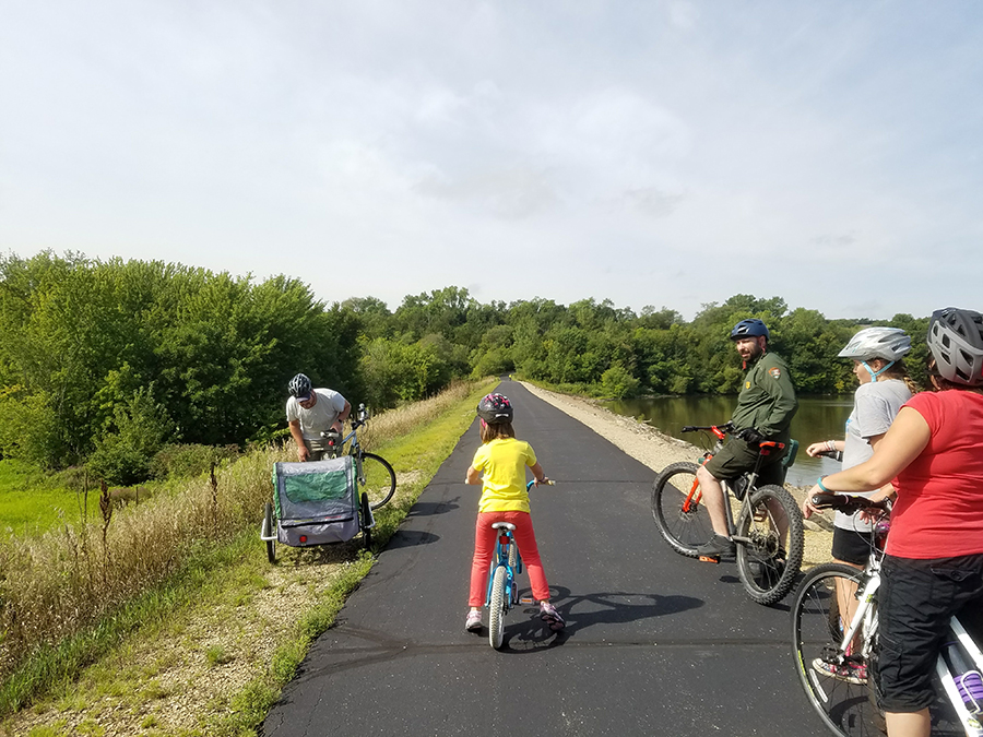 A child and several adults biking on a paved trail with no cars
