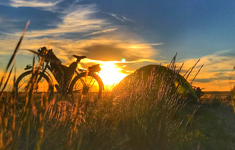 Sunset photo of a bikepacker with camp set up for the night. By Eric Hyde.