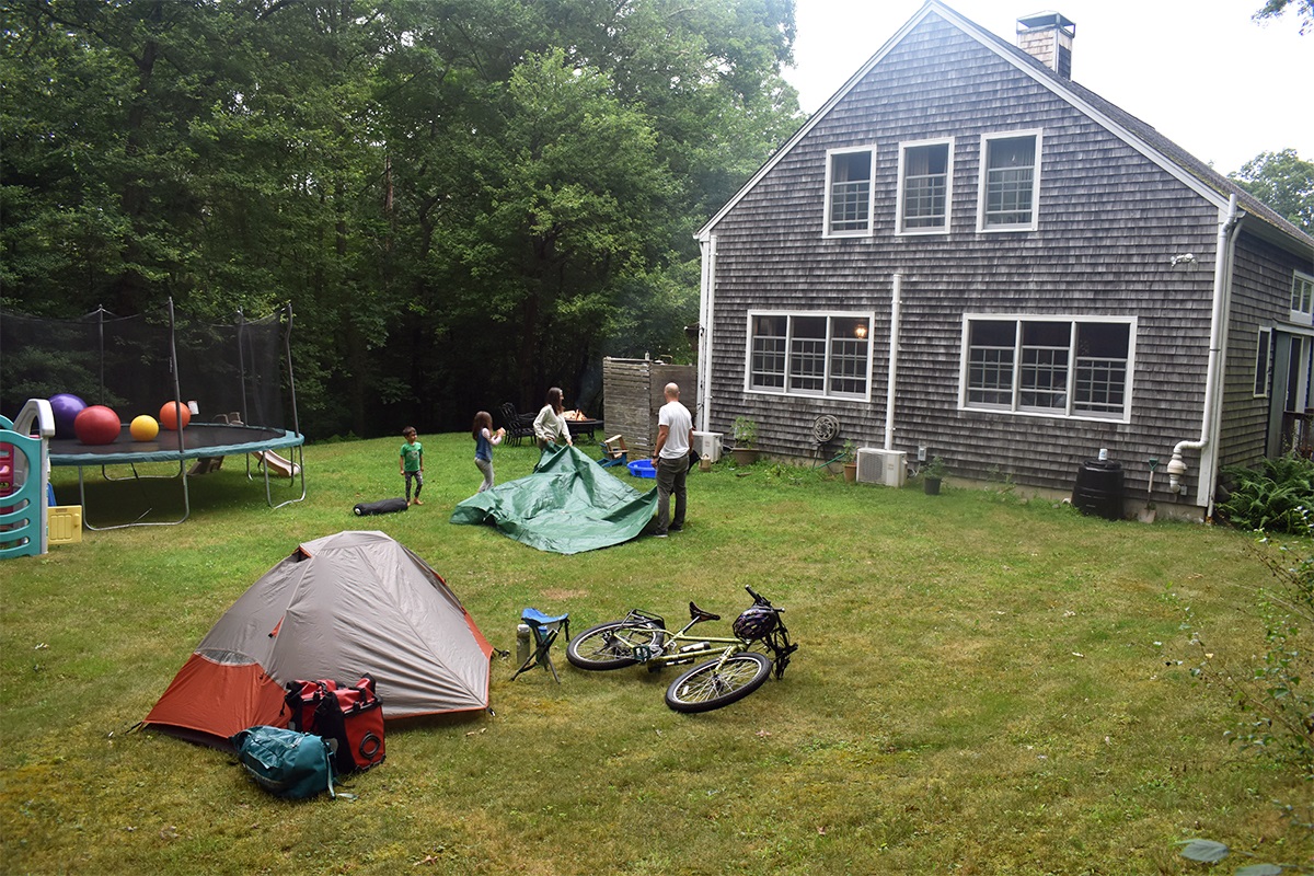 A family sets up a tent in a yard with plenty of social distancing space from the author.