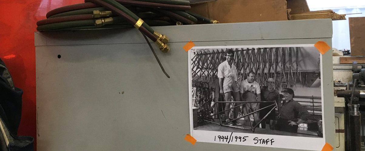 An old photo of 4 goofy young men is taped to a shop filing cabinet