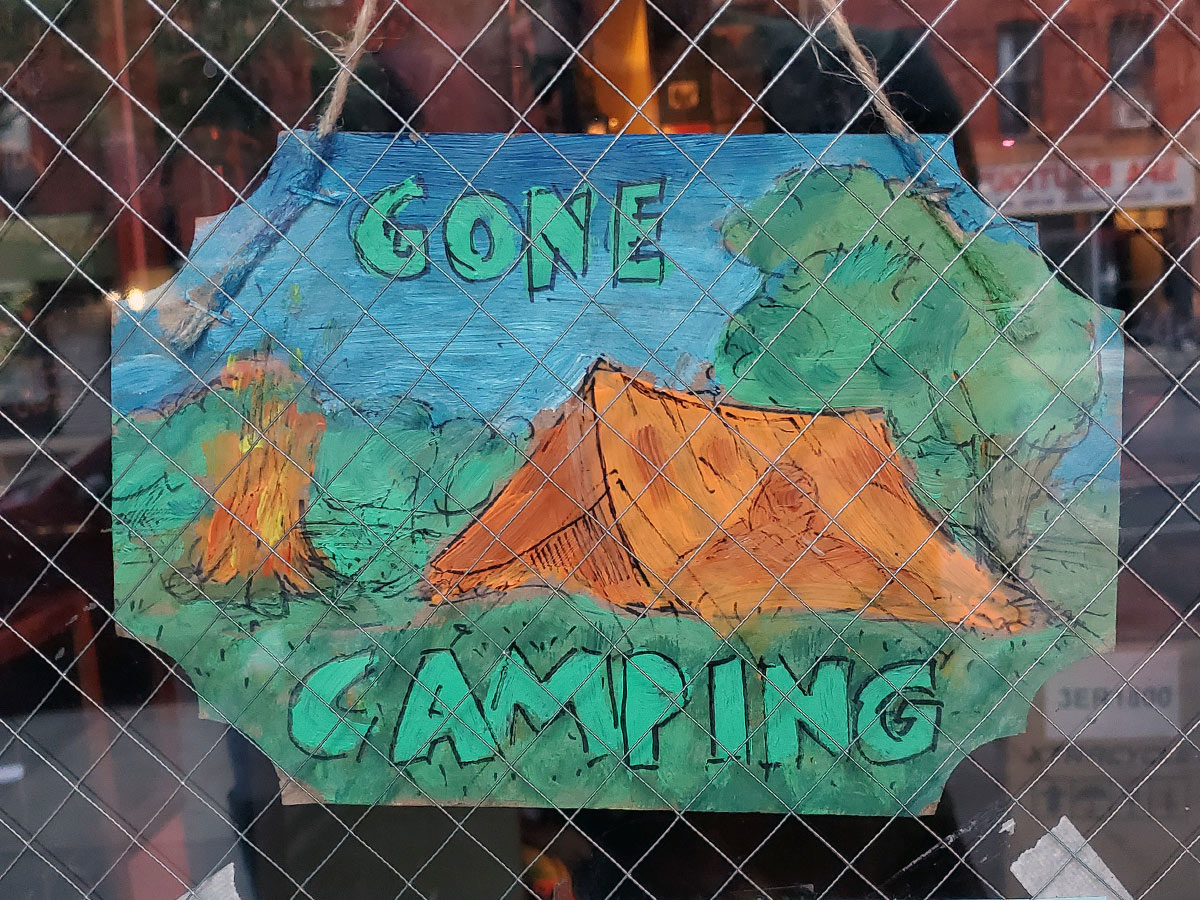 A hand-painted sign in the window of the shop reads "Gone Camping"
