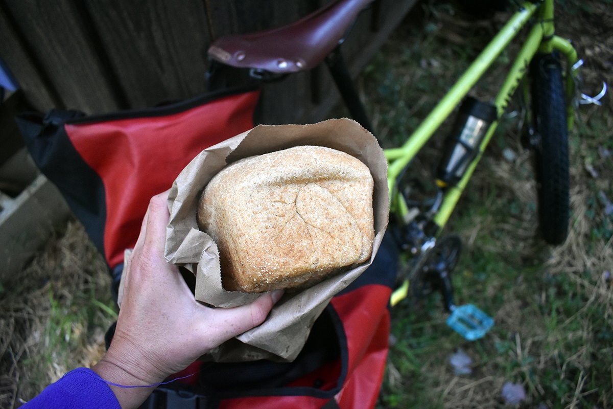Laura pulls an entire loaf of bread out of a pannier