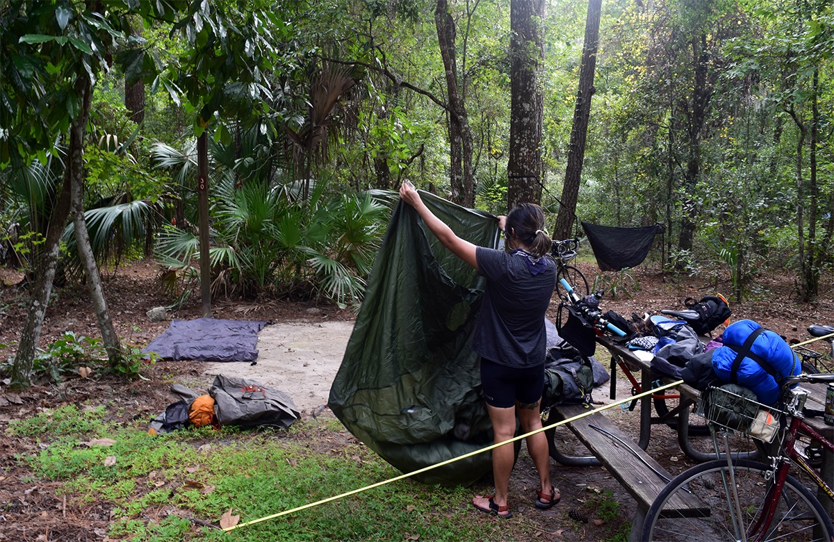 Ana sets up her tent among a lush Florida forest.