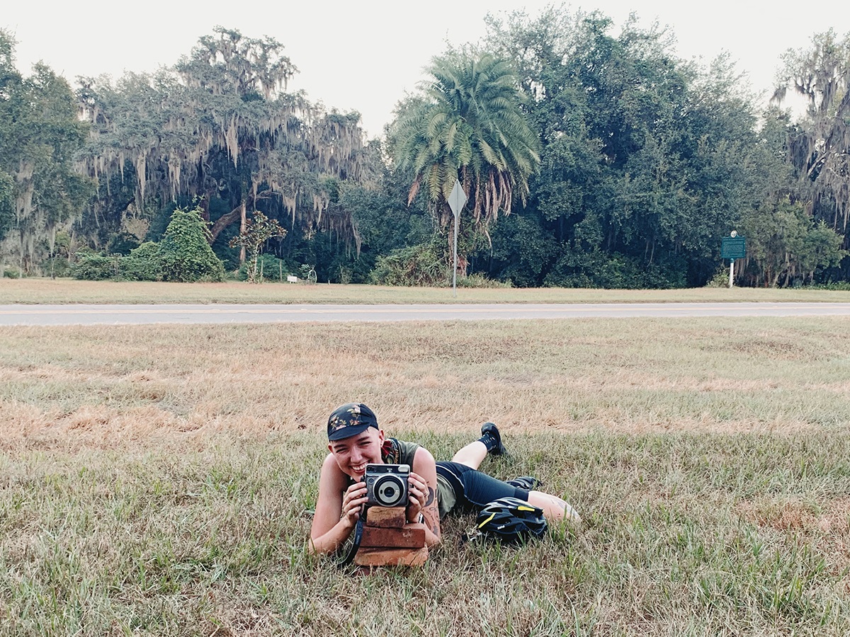 A rider lies in the grass to take a photo.
