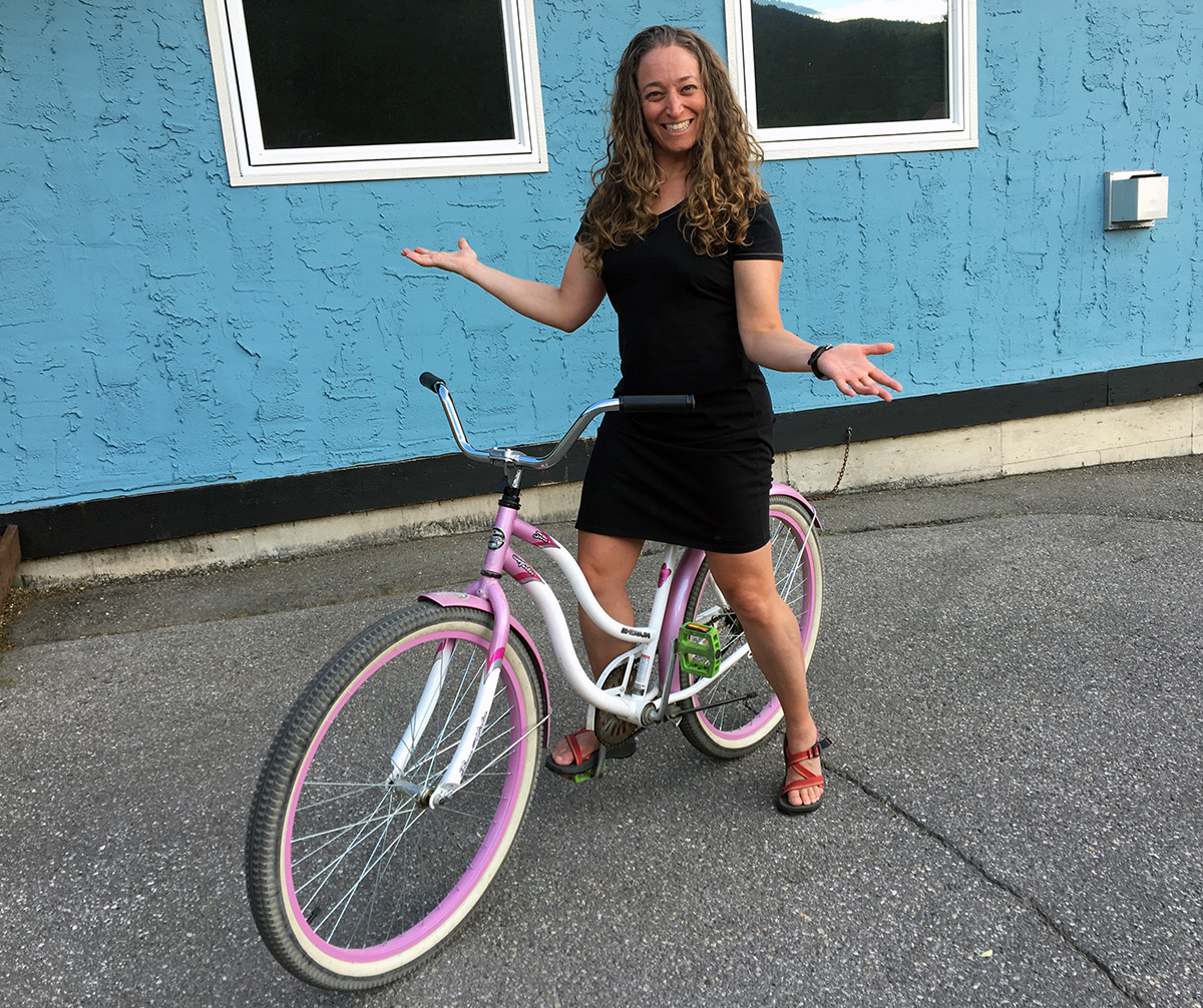 Jessica C Levine stands astride a borrowed beach cruiser bike, wearing her little black dress.