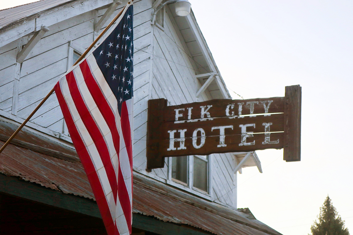 A sign saying Elk City Hotel with an American Flag