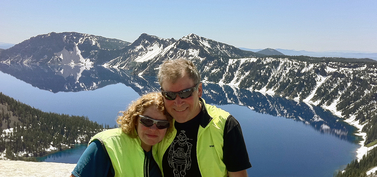 Donna and Jonathan stand in front of a snow-covered Crater Lake.