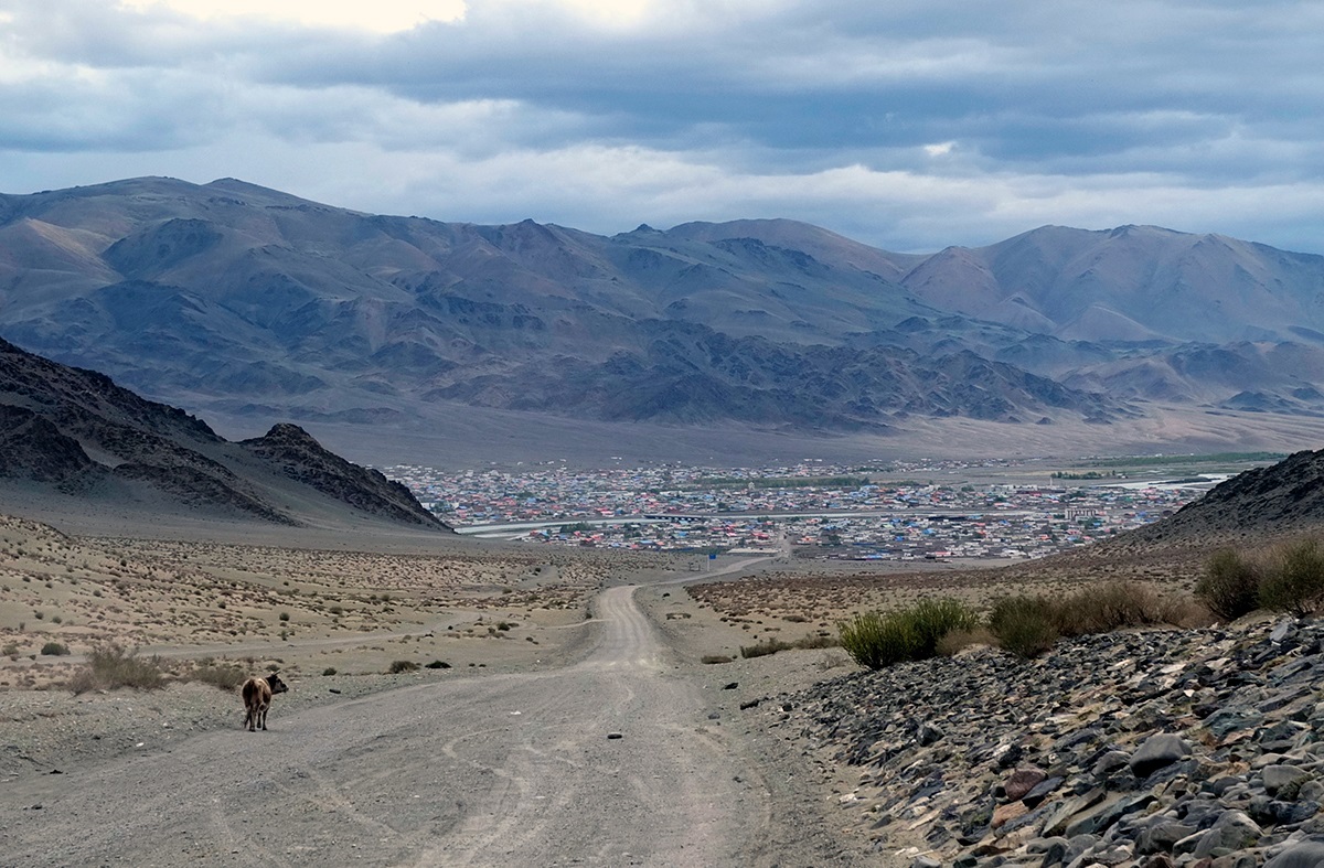 The road into a small Mongolian town surrounded by dusty mountains