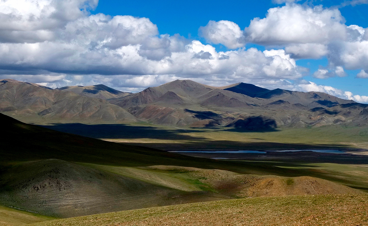 The rolling steppe unfolds against a blue sky