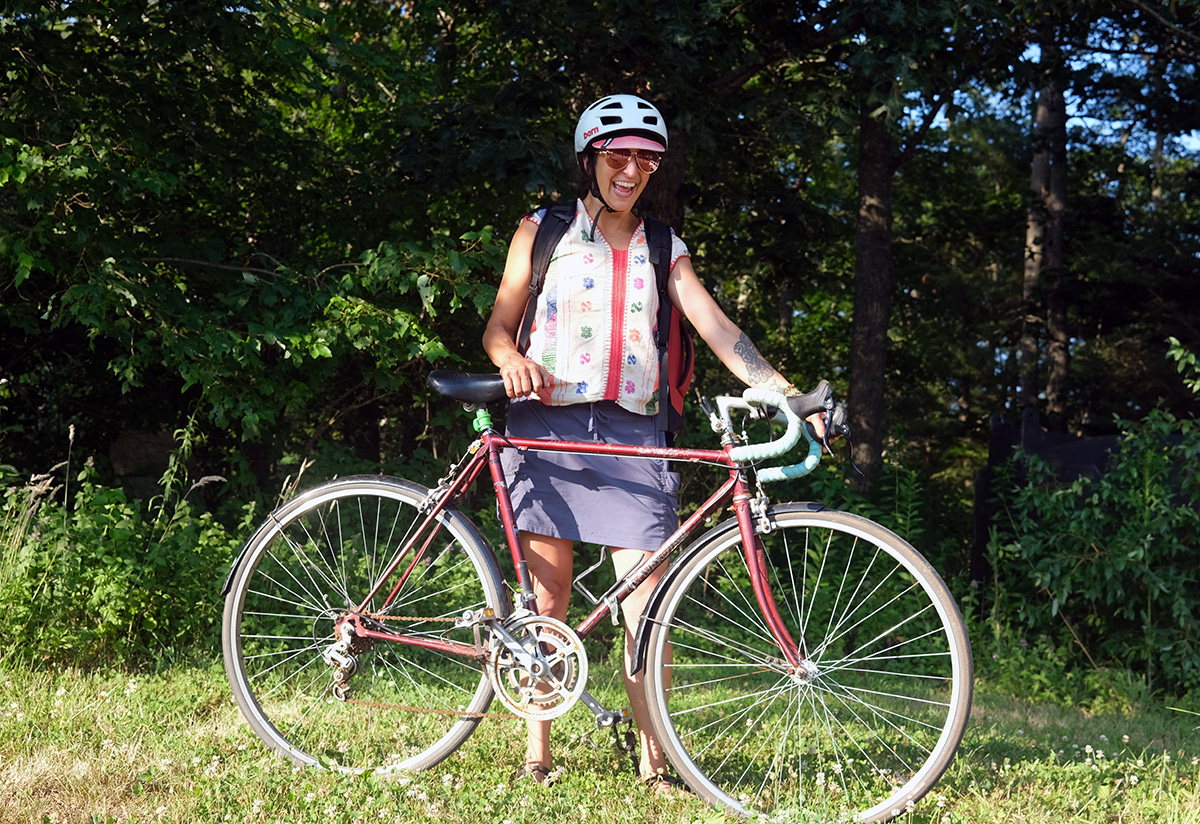 Monica, who is white and female, poses with her vintage red road bicycle
