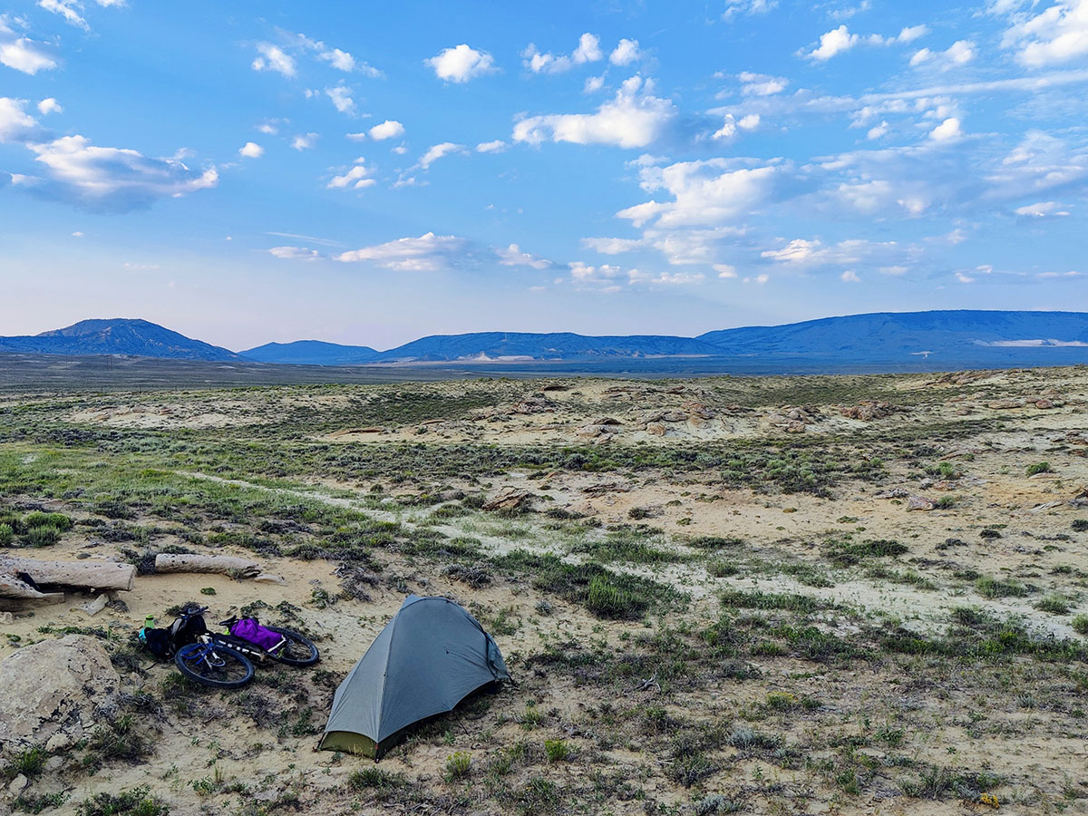 Alissa's tent sits on a wide, empty plain, the only company being some scrubby sagebrush. A blue sky expands overhead.