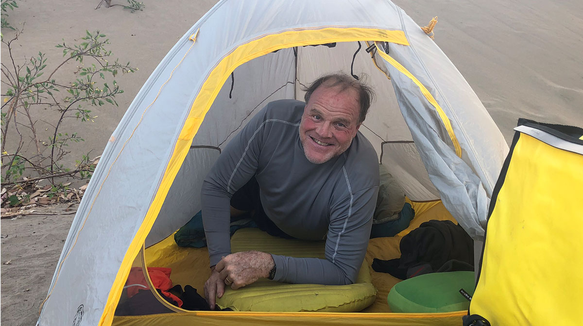 Dad lies in his tent on his first ever night of camping, his head poking out of the tent and a grin on his face.