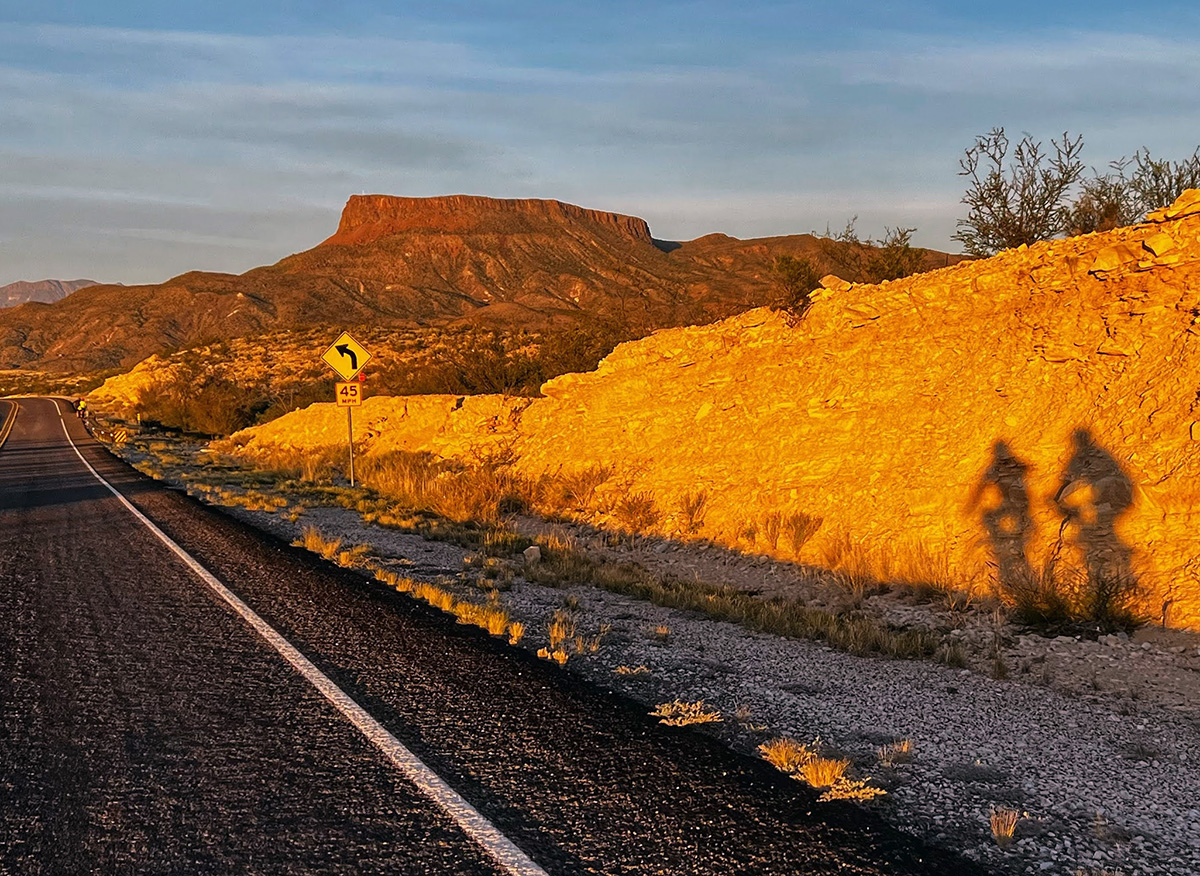 Two cyclist's shadows are seen against a rock in the golden light of the setting sun in Big Bend National Park.