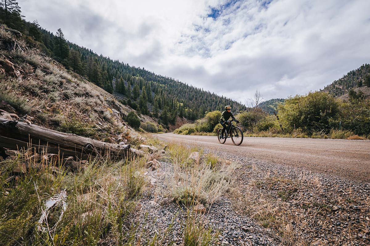 A cyclist passes by on a dirt road among the natural foothills of the rocky mountains