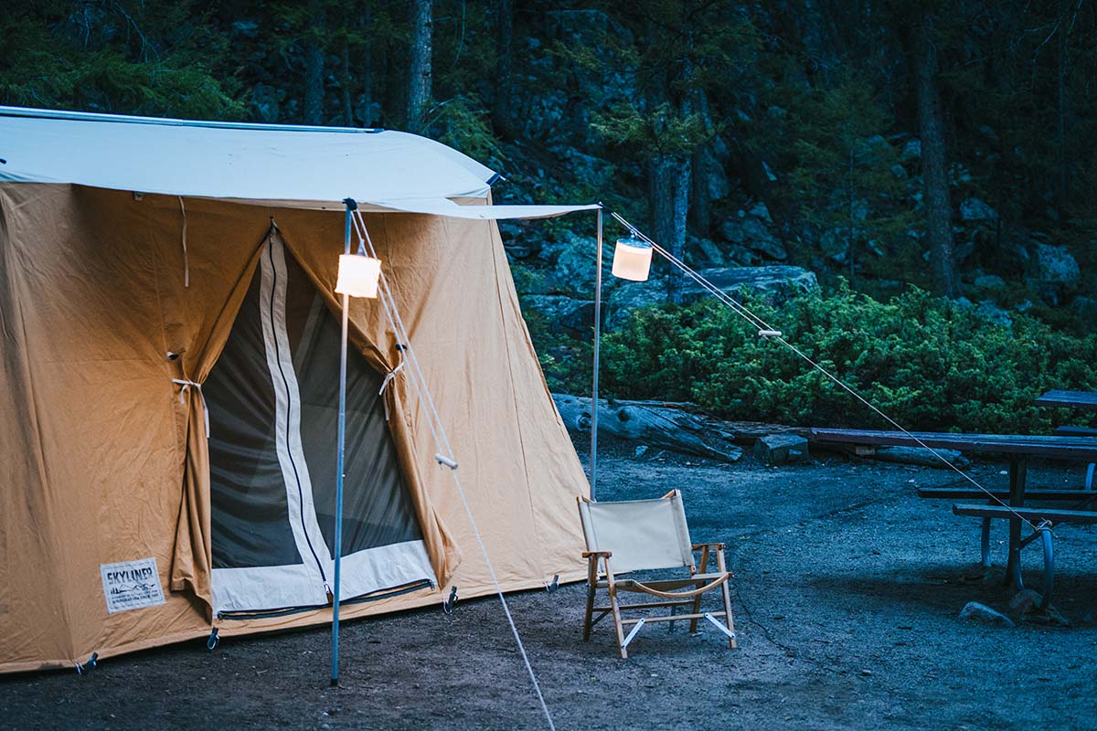 A photo of a wall tent and its open doors at dusk, lit with solar laterns