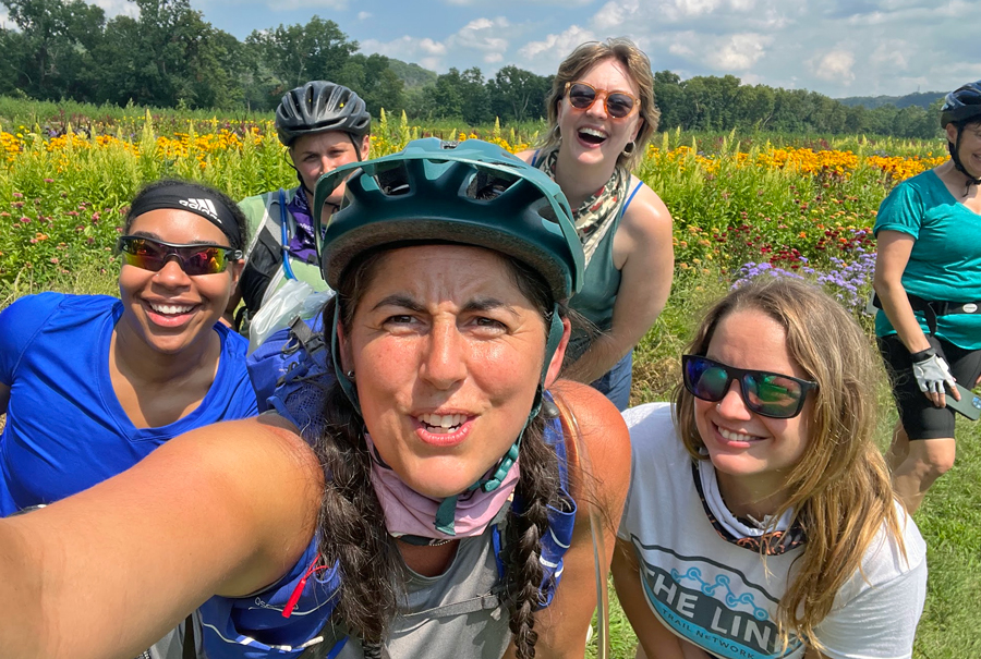 a woman takes a selfie with other cyclists behind her