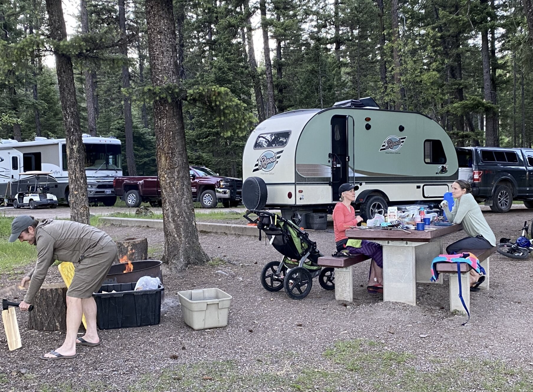 campers and RV and cyclists in a wooded campsite 