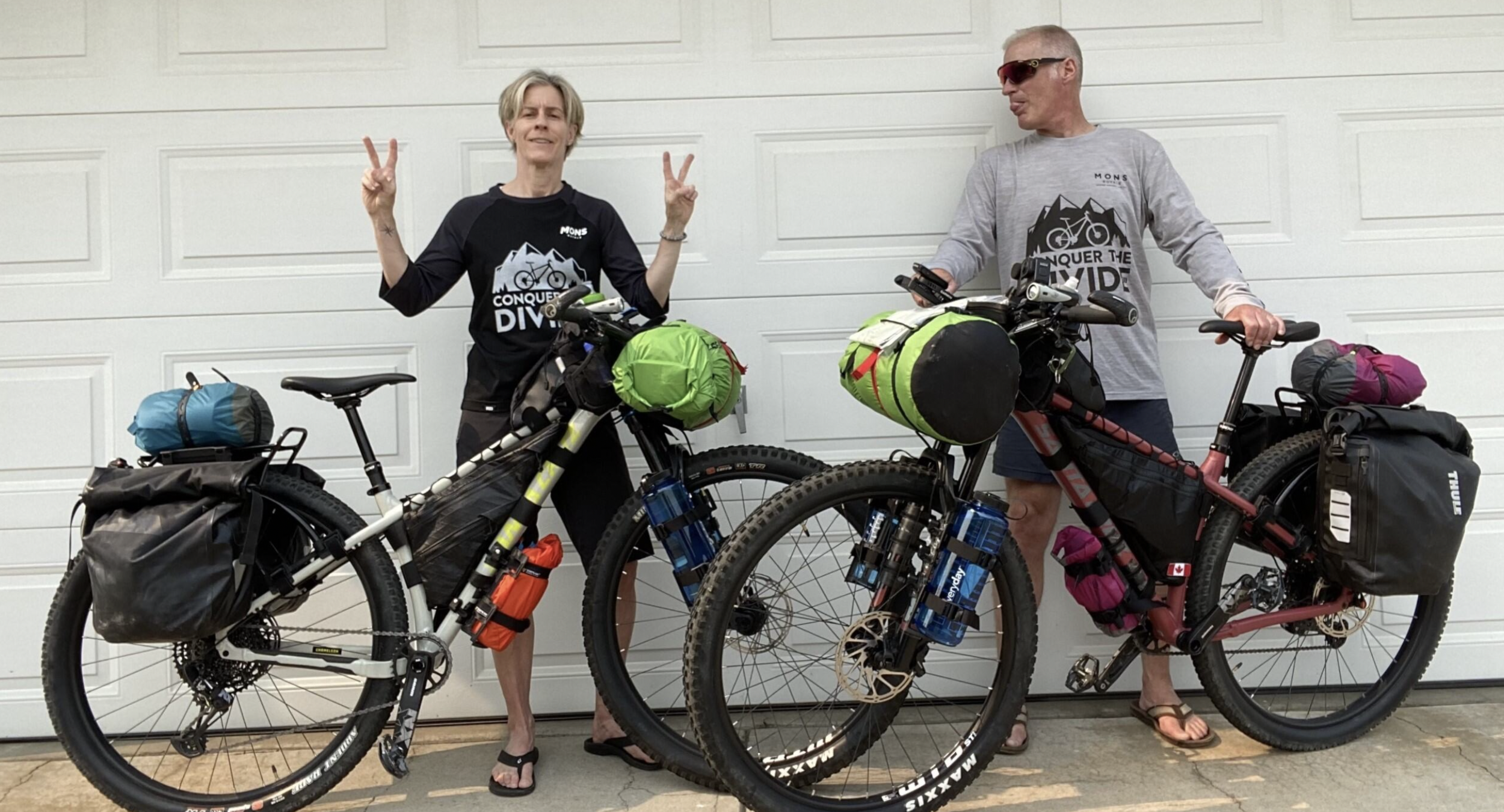 two cyclists stand with their fully loaded bikes 