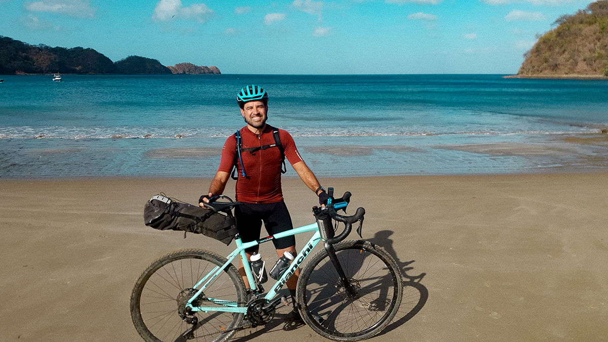 A man smiles on the beach with his Bianchi