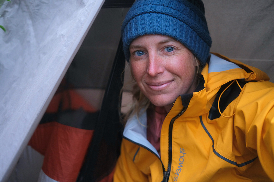 Laura smiling and wearing a knit beanie and bright yellow rain coat.