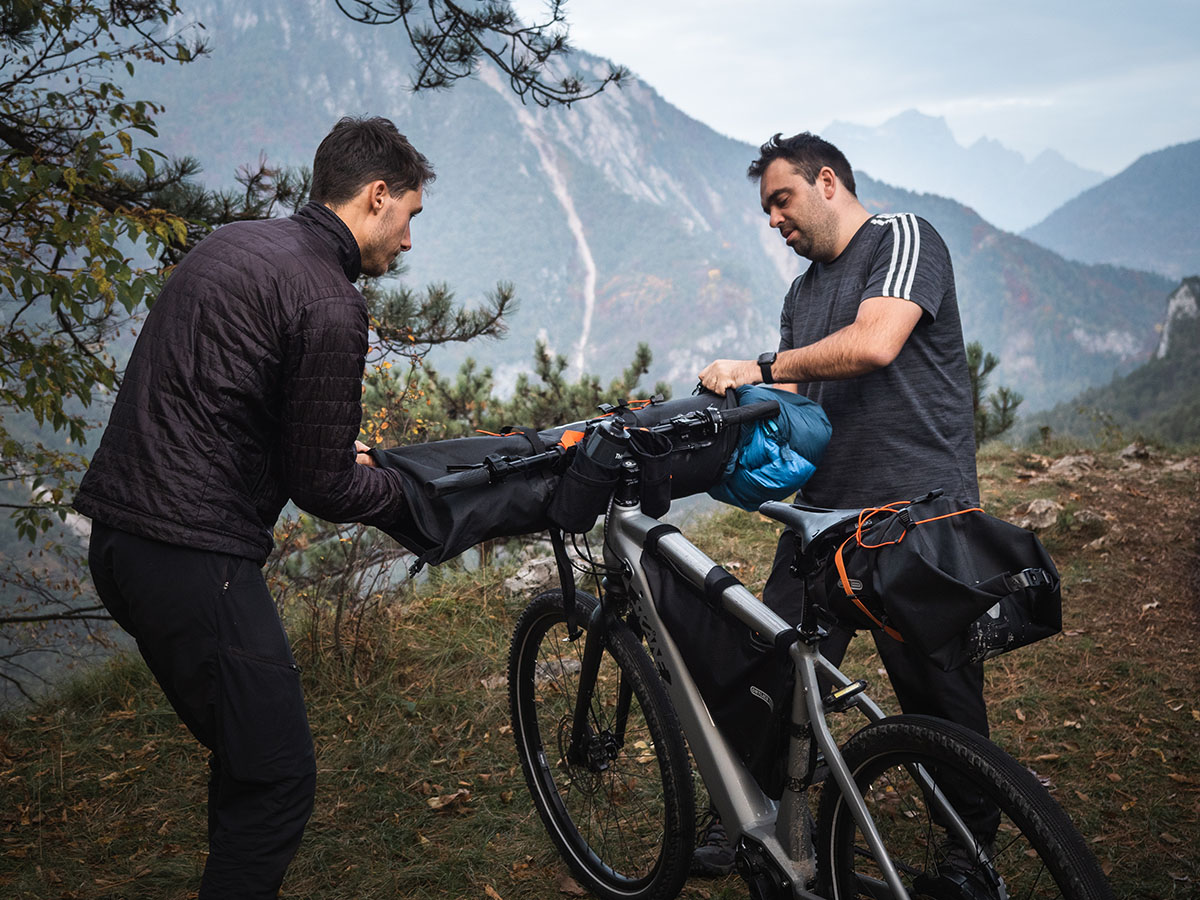 One man gestures at bikepacking bags on other man's bike.
