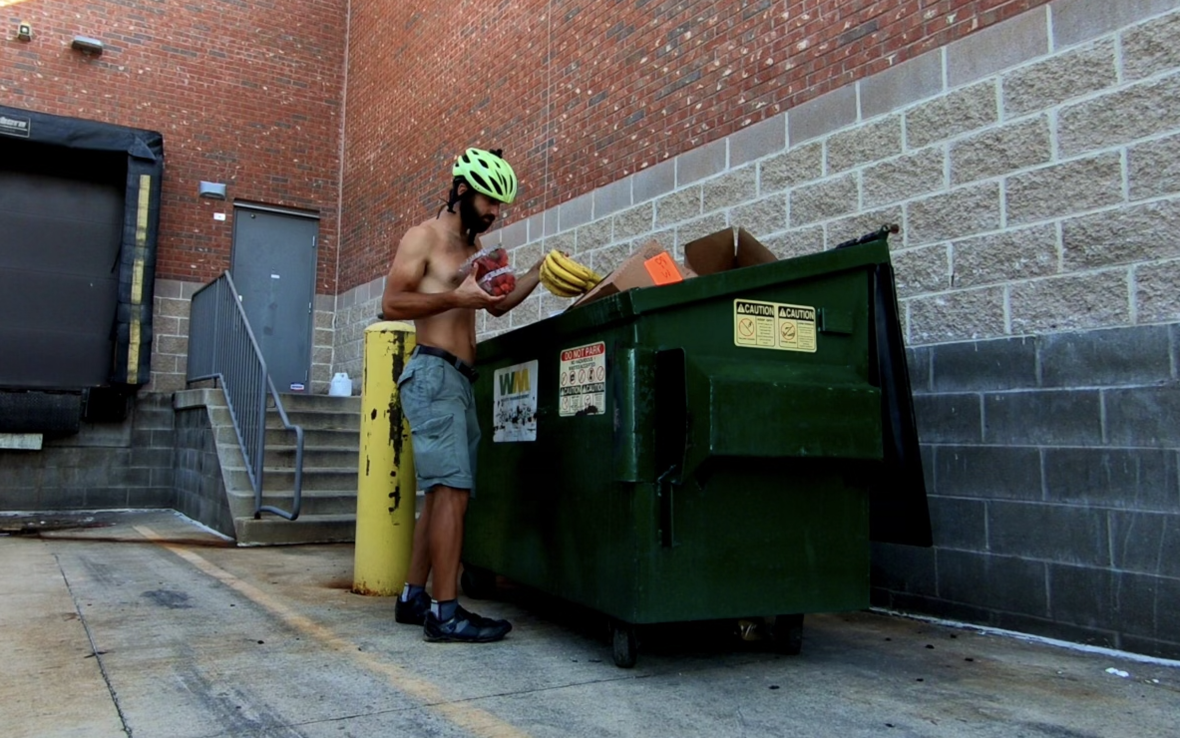 a man in  a helmet by a dumpster