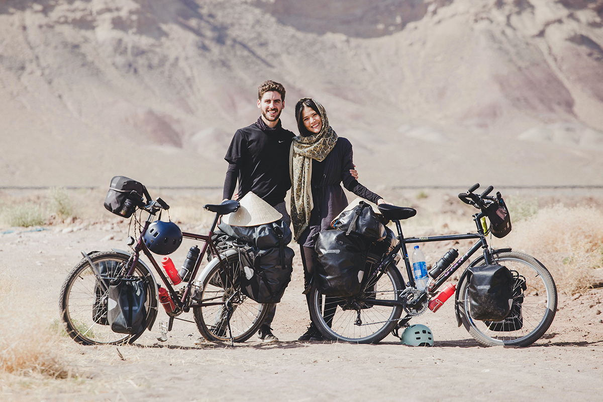 A man and a woman in a head scarf stands next to their loaded bikes