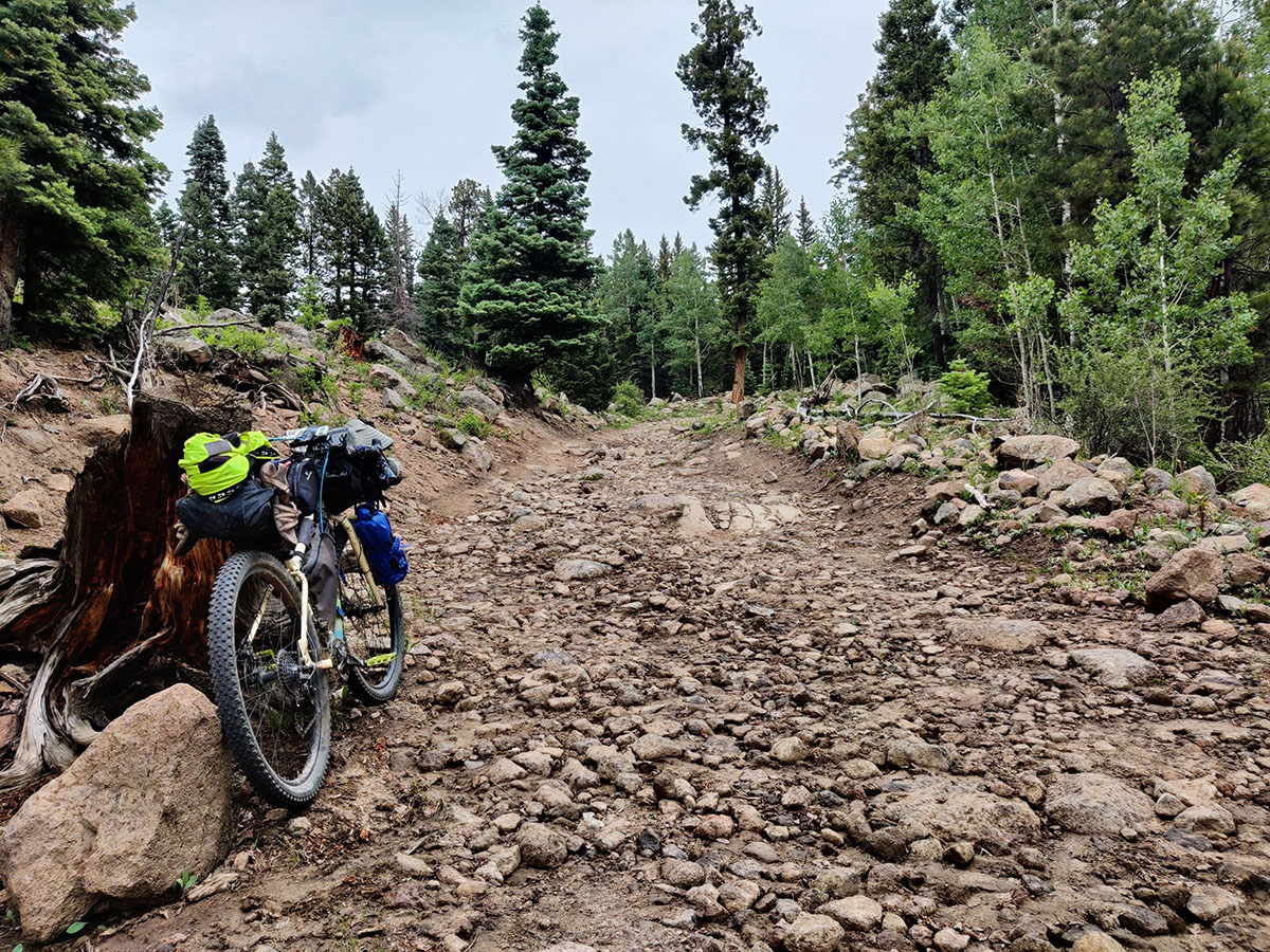 Alissa's bike leans against the bank of the road, or what could be considered a road but also looks like a dry river bed - very rocky and rutted and torn up.