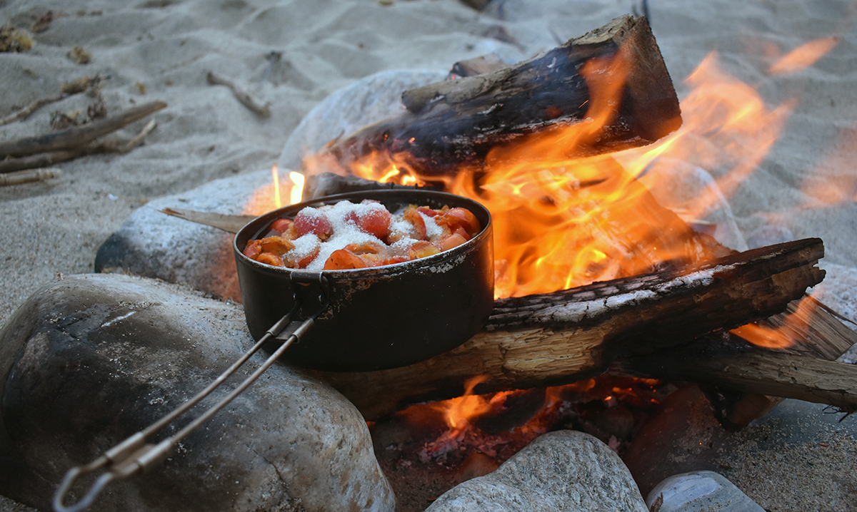 Rose hips are combined with sugar and cooked over a fire to make jam