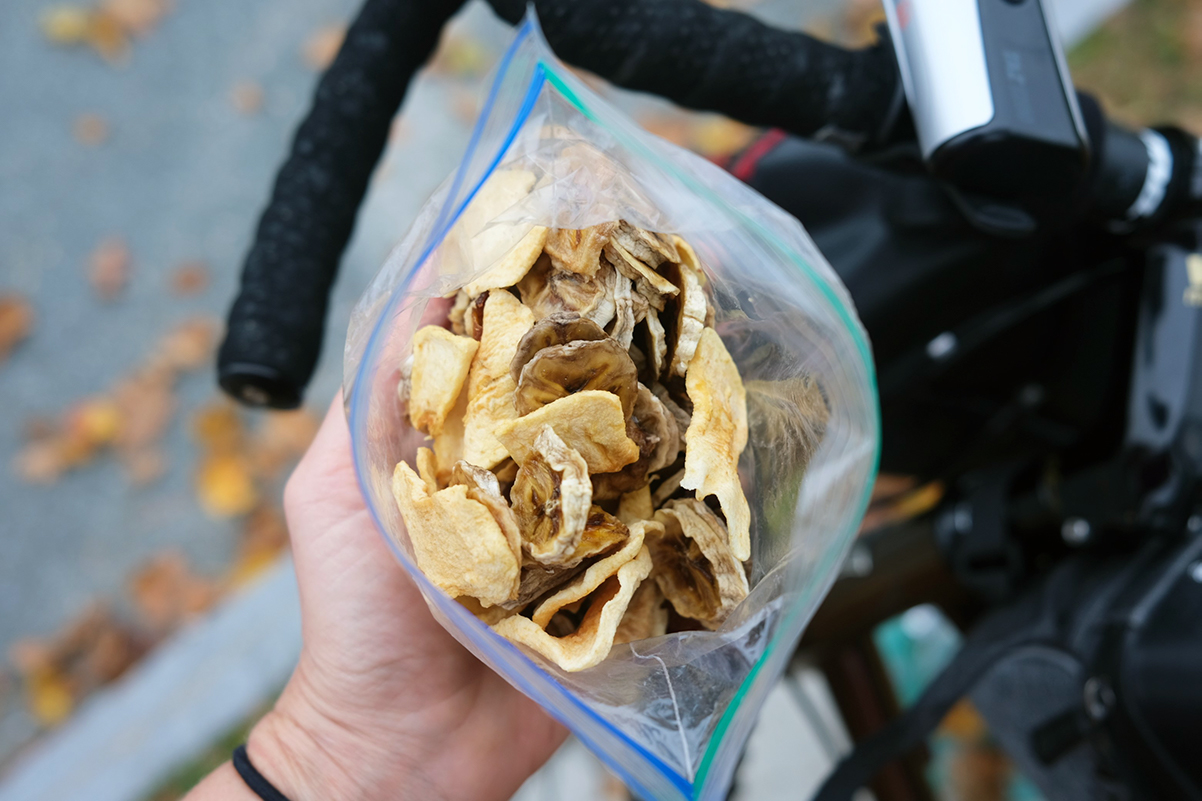 Laura holds a plastic bag with dehydrated bananas and apples.