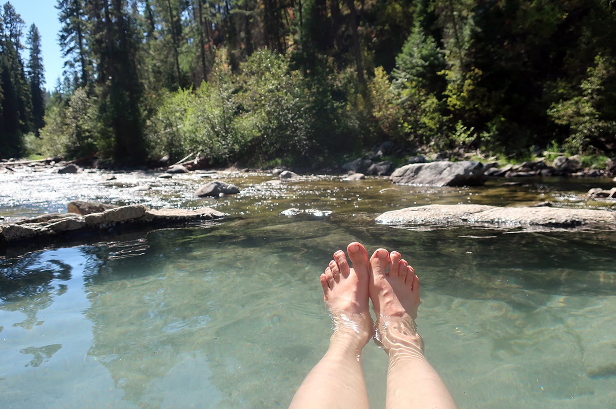 Melissa's feet stick out of a natural hot springs pool.