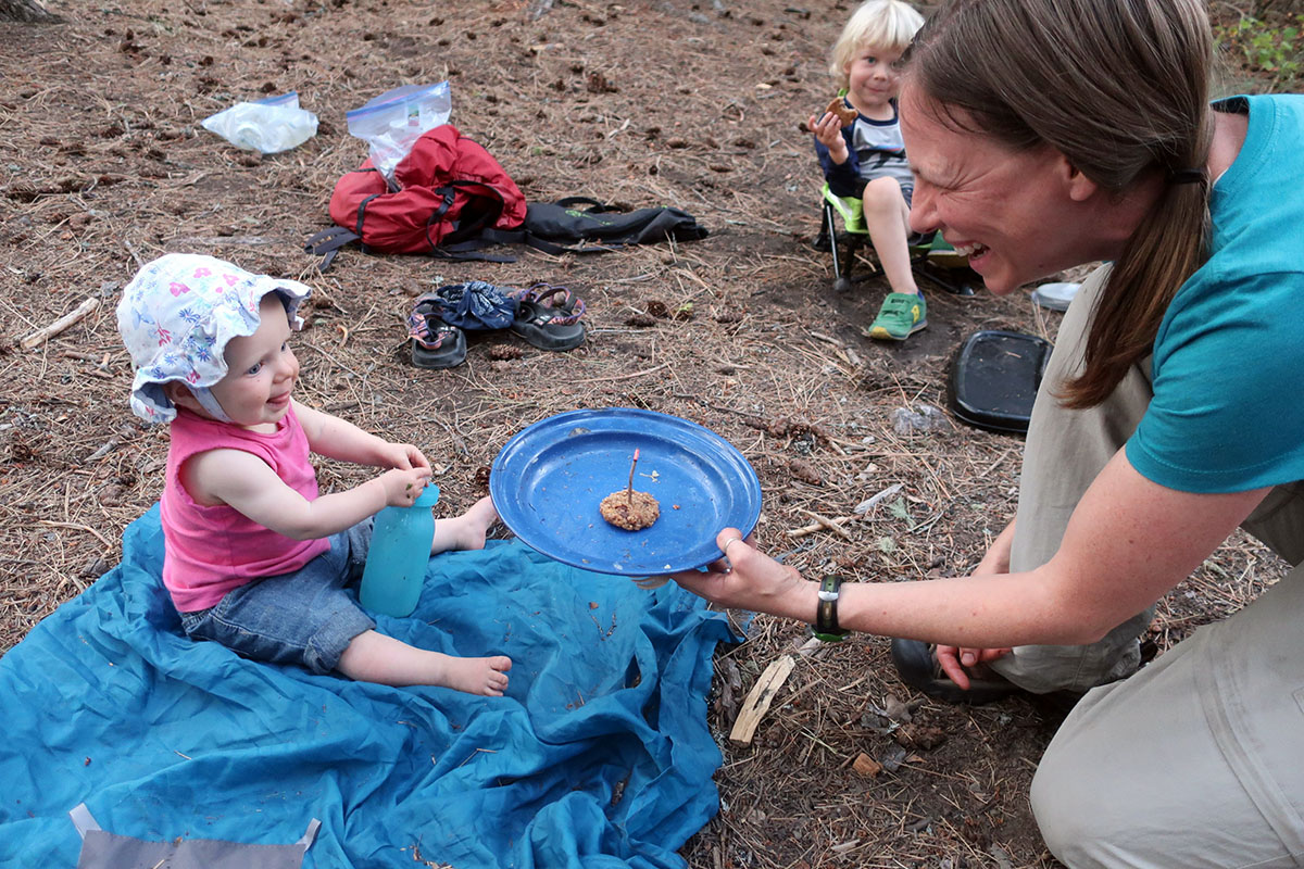 Melissa holds out a cookie with a lit candle to her daughter to blow out.