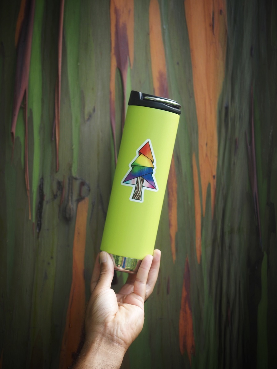 An Outside Safe Space sticker (a pine tree in rainbow color) is featured on a green waterbottle