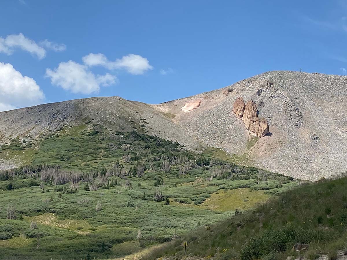 A view of a mountain at a high alpine mountain pass, blue skies all around.