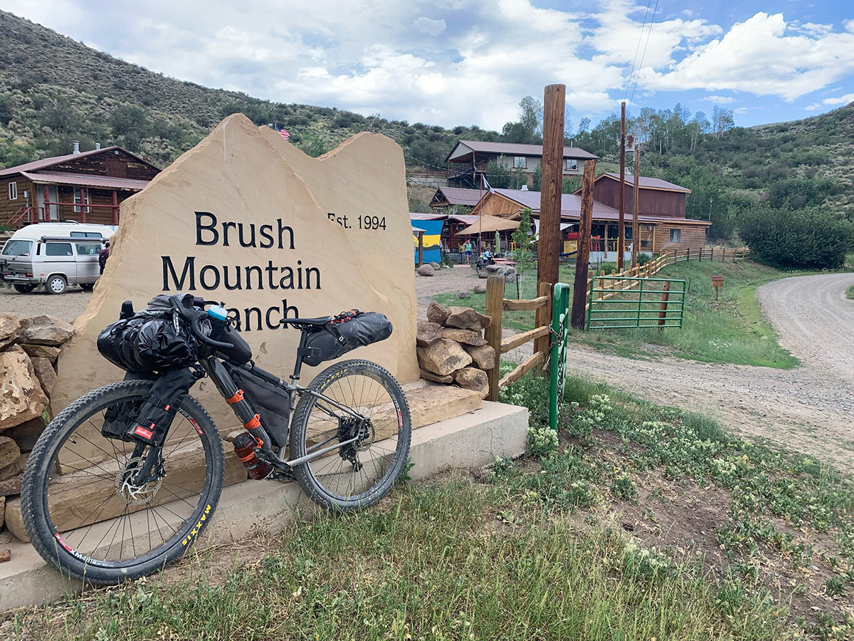 A bike rests against the sign for the Brush Mountain Ranch, a common stop for riders on the Great Divide.