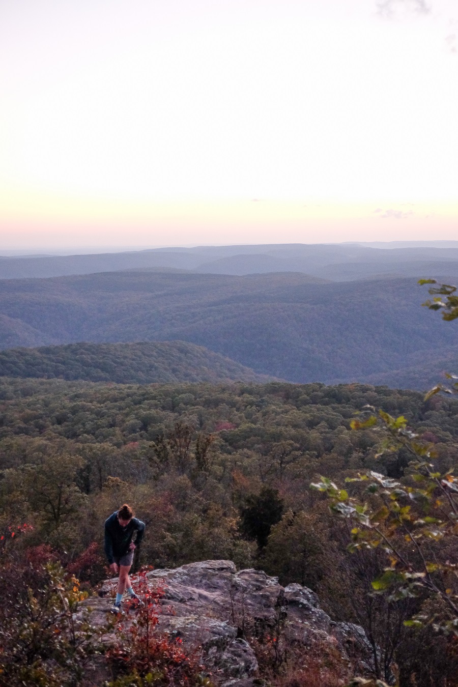 Jessica's friend Nicole hikes up the cliffs with a beautiful golden sunset behind her in the White Rock Recreation Area on the Adventure Cycling Arkansas High Country Route