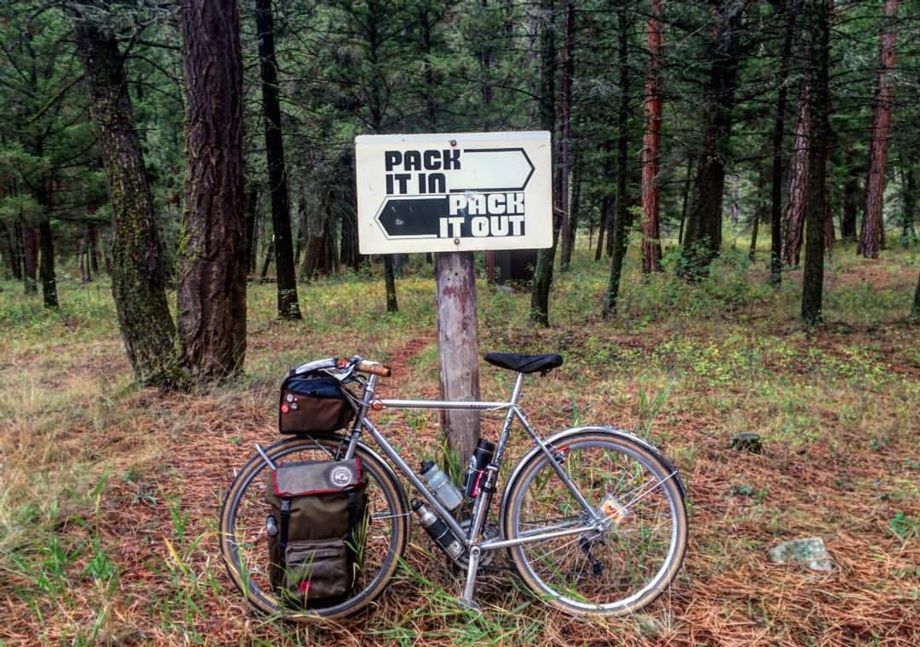 Bike leaning against a sign saying "Pack it in. Pack it out."
