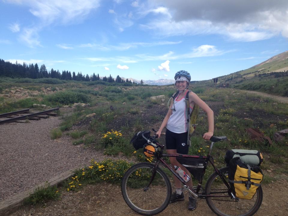 Woman standing next to her bike in a brushy landscape.